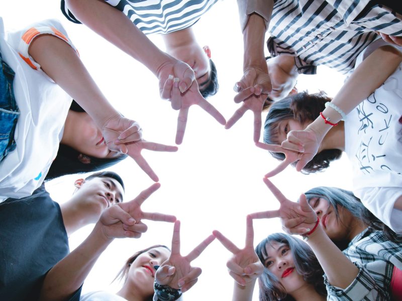 A circle of friends forming a star shape with fingers, symbolizing unity and teamwork.